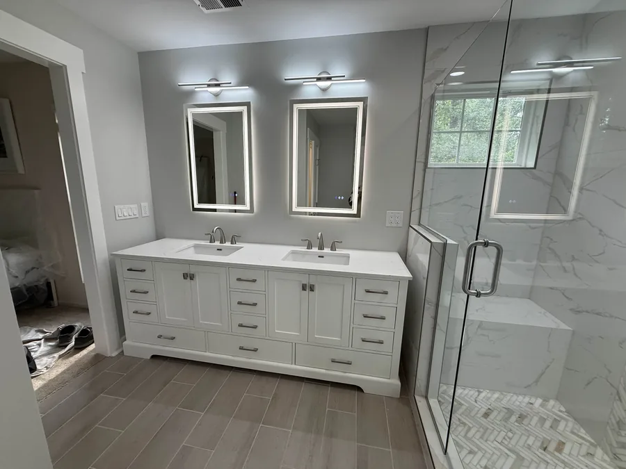 Bathroom remodel with double vanity, LED mirrors, and tiled walk-in shower